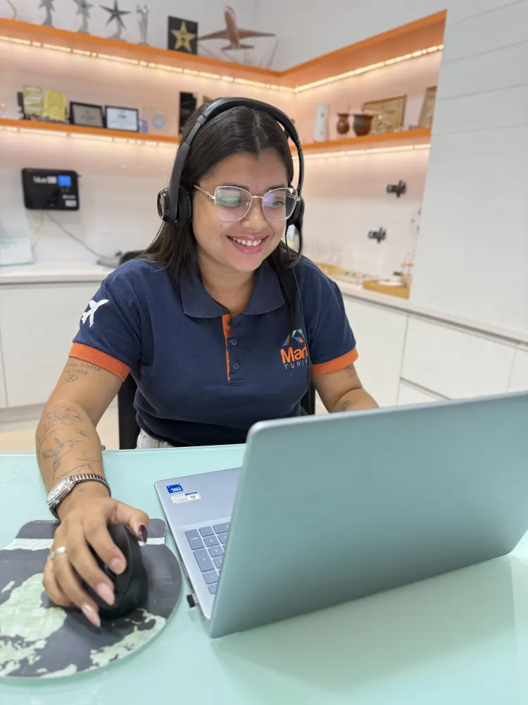Consultora da Maritê Turismo com headset atendendo cliente pelo computador